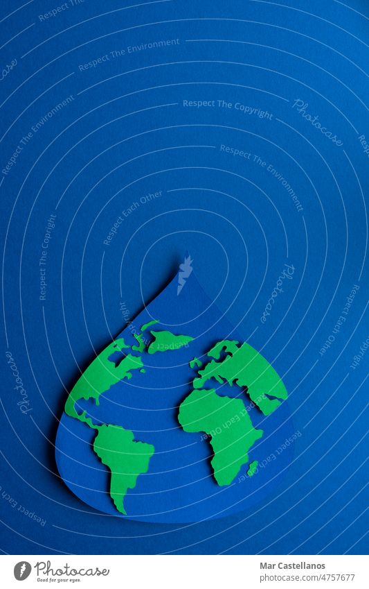 Water drop cut out on paper with world map on dark blue background. International Earth Day. Copy space. Vertical photo. earth global design life april