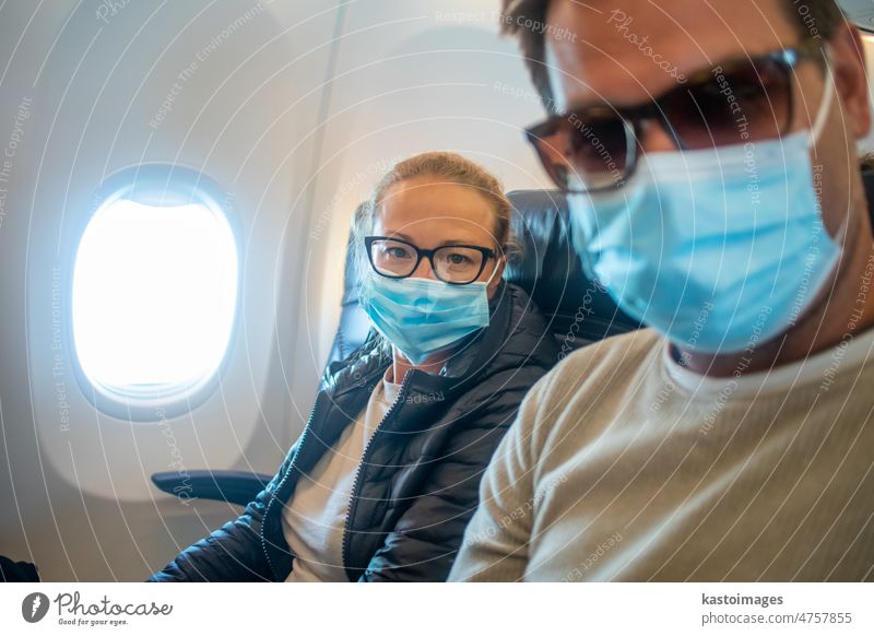 A young couple wearing face masks while traveling on airplane. New normal travel after covid-19 pandemic concept traveler tourist transport woman tourism