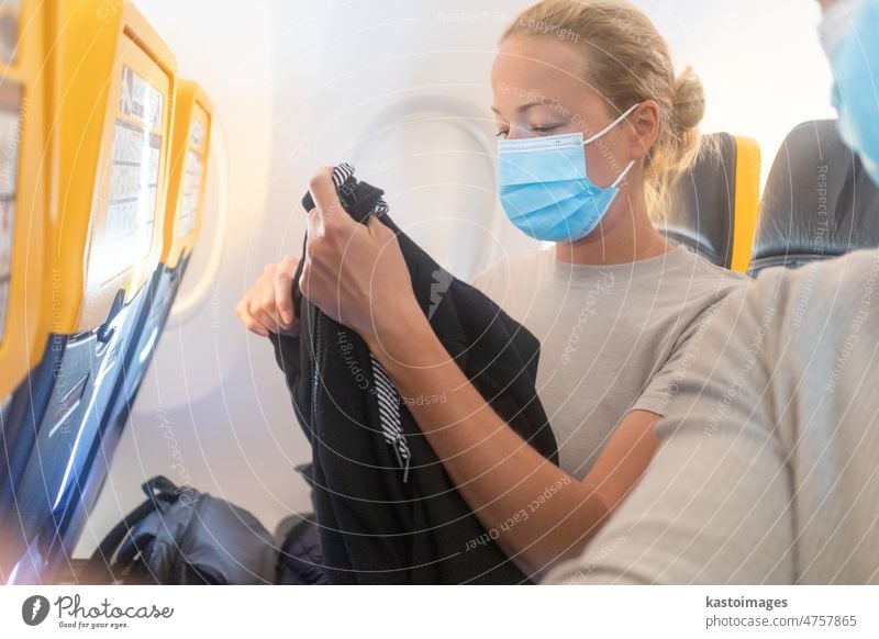 A young woman wearing face mask while traveling on airplane. New normal travel after covid-19 pandemic concept traveler tourist transport tourism passenger