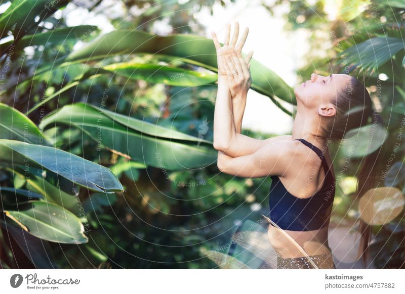 Female meditating and practicing yoga in tropical rainforest. Beautiful young woman practicing yoga outdoor with tropical forest in background. retreat
