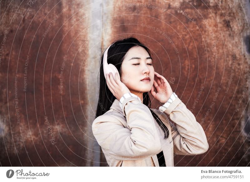 relaxed business woman with eyes closed listening to music on headphones and mobile phone in city chinese head phones happy smiling crossing street urban