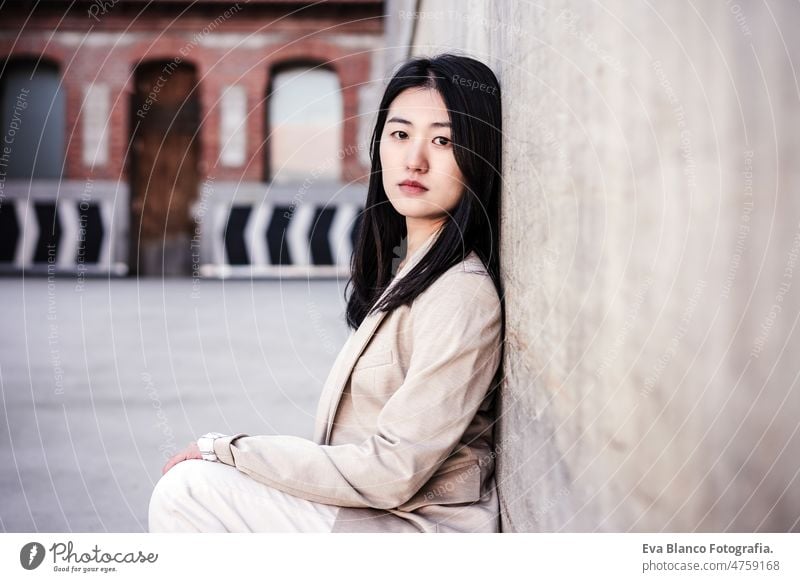 portrait of confident chinese woman in city leaning on wall lifestyle modern business entrepreneur asian beautiful ethnic international face attractive hopeful