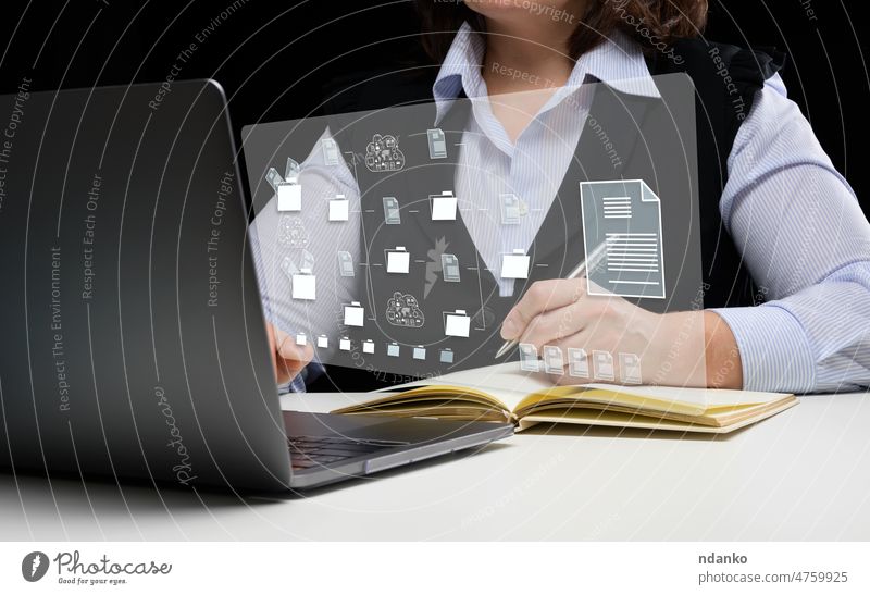 Woman sits at a table and works with a laptop. Document management mystem (DMS). Software for automating archiving and efficient management of information files