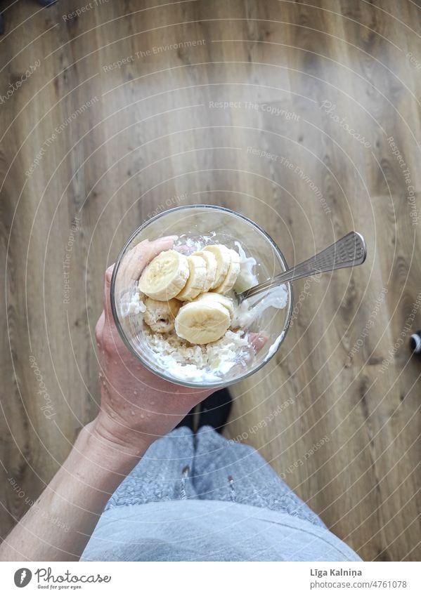 Top view of hand holding porridge in glass with banana and yoghurt Porridge healthy Breakfast bowl background Diet fruit Cereal breakfast food Nutrition oatmeal
