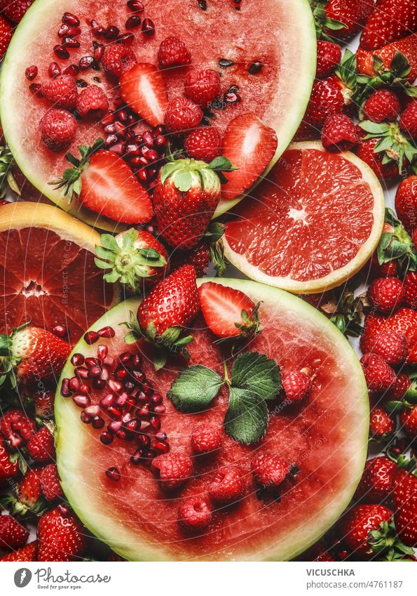 Red fruits and berries background. Healthy summer food red watermelon grapefruit strawberries raspberries pomegranate seeds healthy top view berry delicious