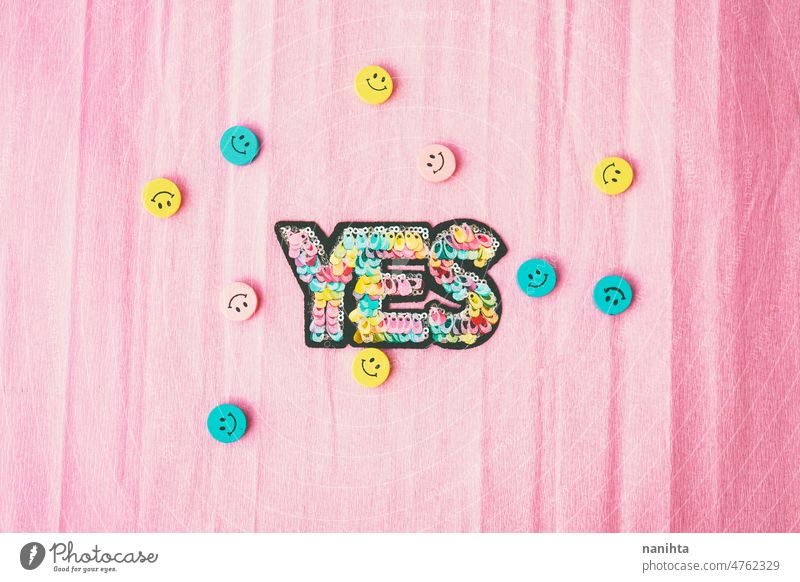 Word "yes" make with colorful sequins and surrounded by smiley faces word happiness positive wellness diy pastel tones design patch pink yellow blue cyan happy