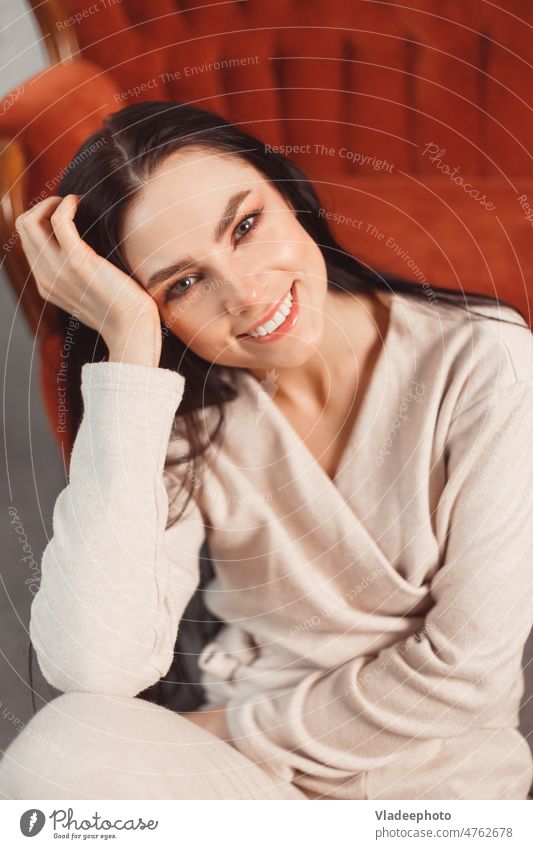 Woman indoor portrait. Young beautiful woman in warm cashmere clothes at home. fashion. Autumn, winter brunette kerseymere cozy sofa coush smile alone autumn