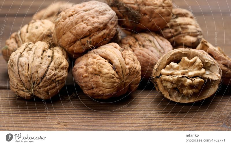 walnut on brown wooden table, close up kernel autumn broken closed closeup cracked delicious diet dry food fresh fruit group hard harvest healthy ingredient