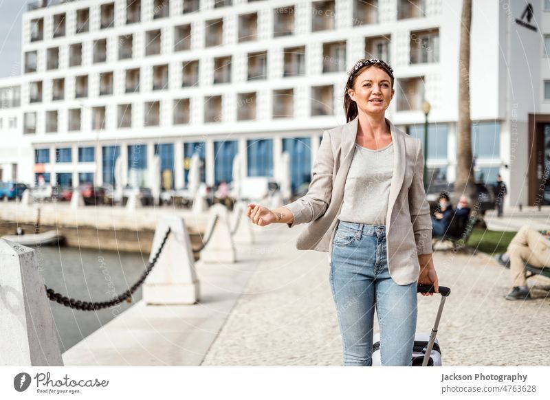 A portrait of a young happy woman walking with the luggage in urban settings bag traveler smile street hotel baggage fashion confident outdoor city break