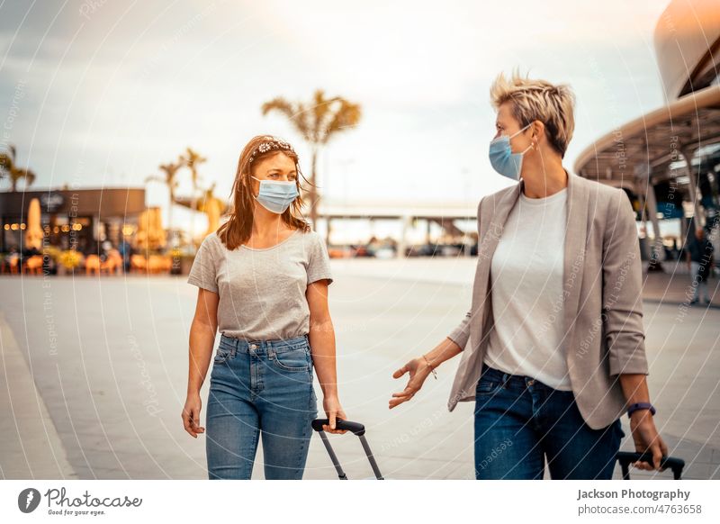Traveling women in protective masks with luggage talking on the way from airport travel friends woman covid covid-19 pandemic lifestyle commuter traveler happy