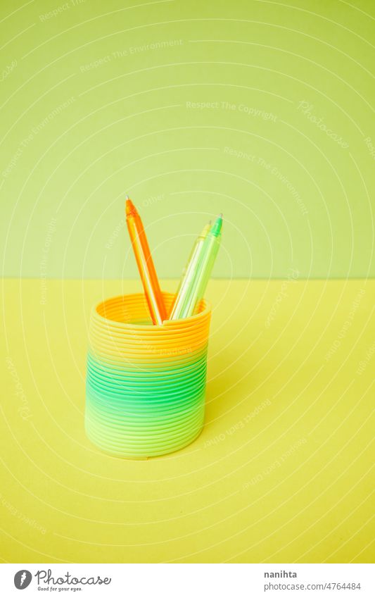 Colorful pens inside a colorful slinky toy fluor childhood remember retro orange green lime yellow flat background abstract chape circle spiral school material