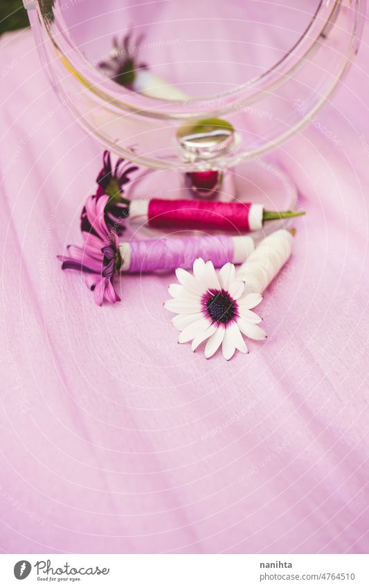 Still life of flowers, sewing threads and a beauty mirror in trendy seasonal tones couture floral purple palette still life design trends fashion