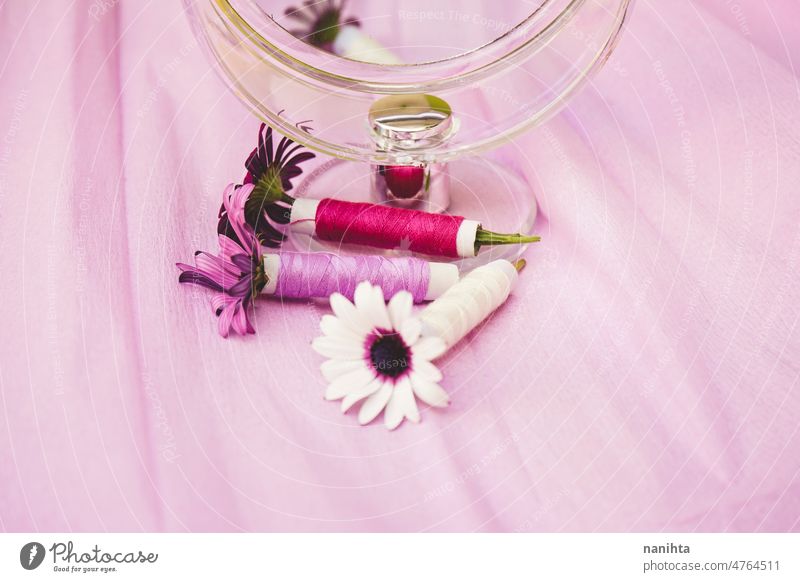 Still life of flowers, sewing threads and a beauty mirror in trendy seasonal tones couture floral purple palette still life design trends fashion