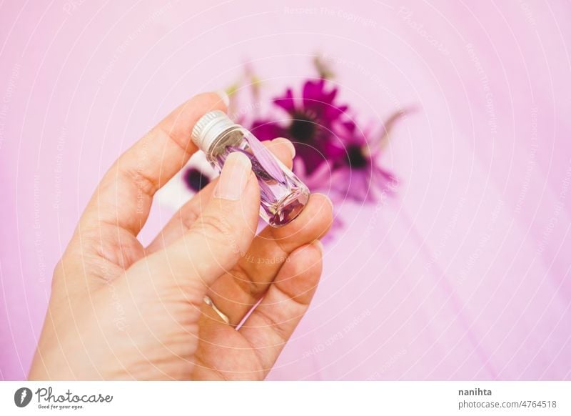 Close up of a hand holding an aromatherapy bottle filled with water and petals essential oil floral flower sample spring springtime fragrance natural eco bio