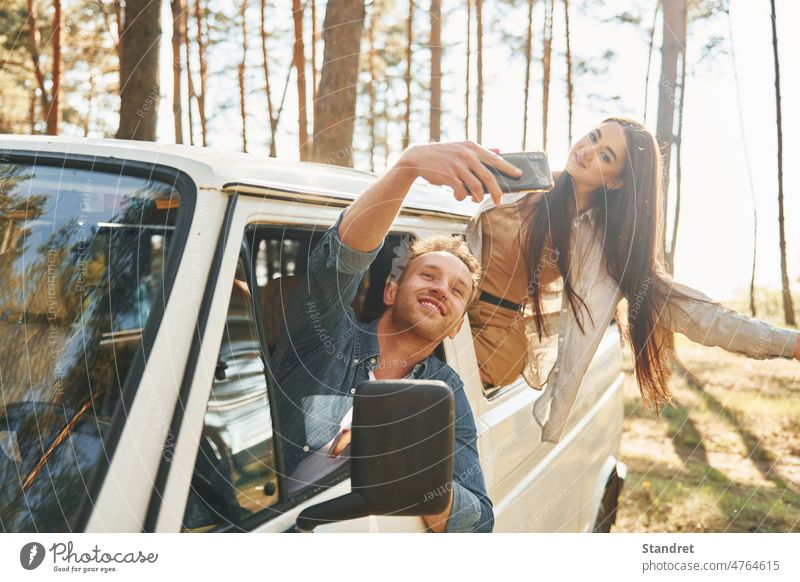 Making selfie. Young couple is traveling in the forest at daytime together tourist adventure human car vehicle people group friends discover summer spring trees