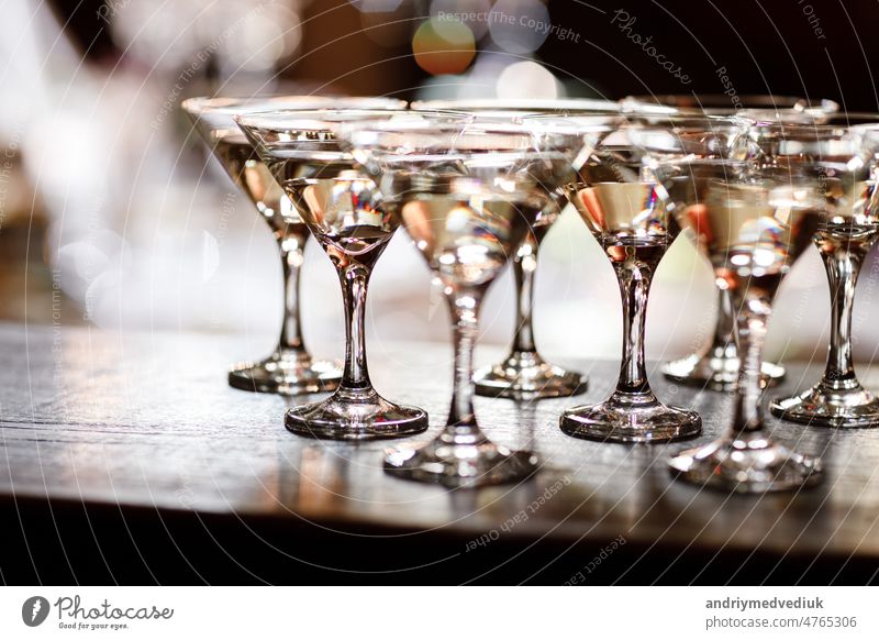 martini glasses in front of gold bokeh background. Luxury cocktail drink in restaurant bar with night lights blur. Classy beverage celebration party for new year, christmas, valentine.