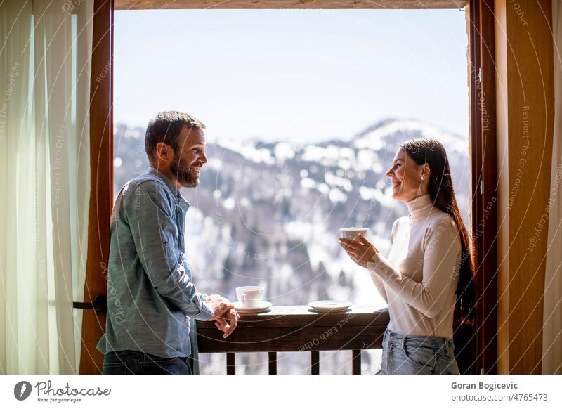 Young couple with cups of hot tea at winter window apartment attractive beautiful beverage calm coffee cute drink enjoying face female home hotel house interior