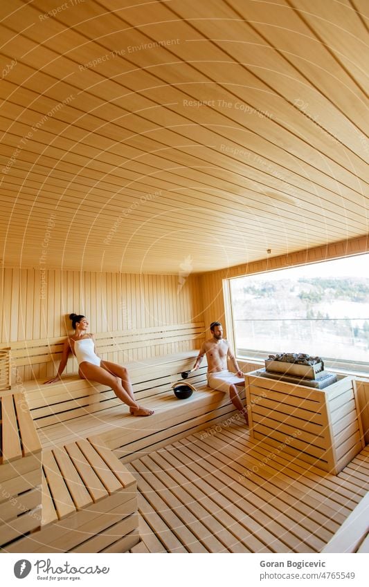 Young couple relaxing in the sauna and watching winter forest through the window adult bath beauty body cabin caucasian finland finnish frozen guy health