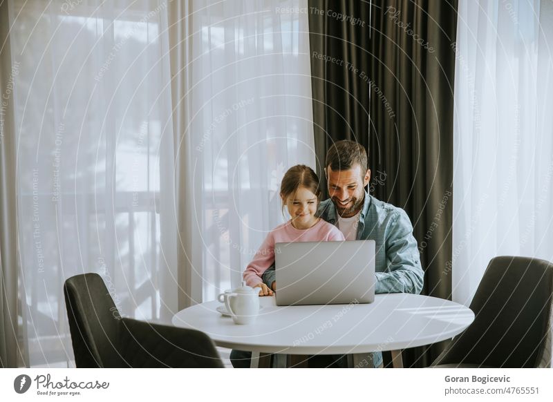 Father and daughter using laptop computer together father man smiling girl dad technology home child family parent young happy browsing sofa people room