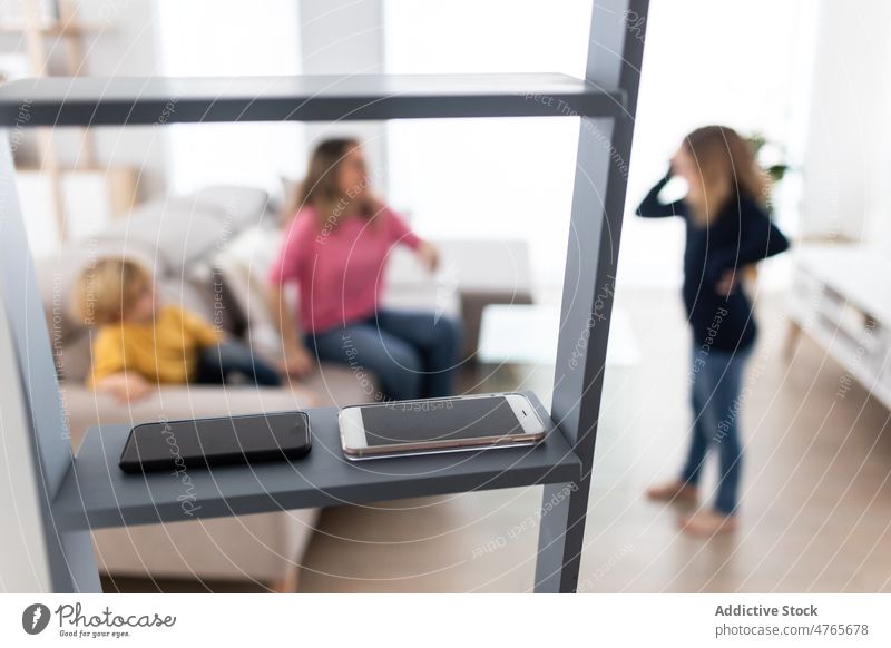 Smartphones on ladder in room with mother with children smartphone living room childhood spend time digital detox pastime abstinence disconnection apartment