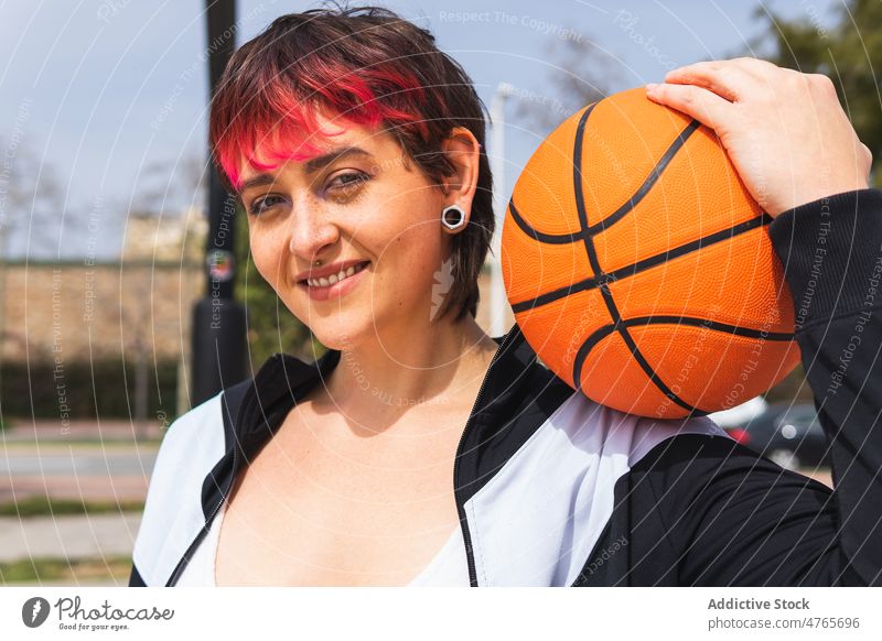 Positive lady with basketball on street sportswoman smile player streetball positive portrait female lifestyle dyed hair equipment hobby wellness personality