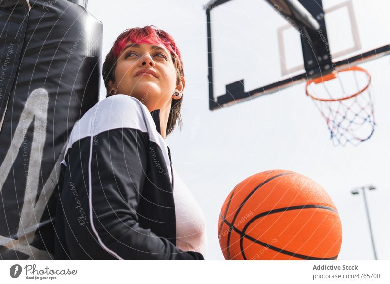 Ponder female with ball on basketball sports ground sportswoman player dreamy streetball think hoop game sky practice training activity lifestyle fit ponder