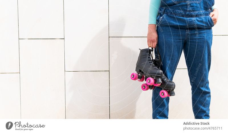Anonymous female carrying rollers against building wall woman roller skate quad roller hobby sporty lifestyle active tile activity casual individuality