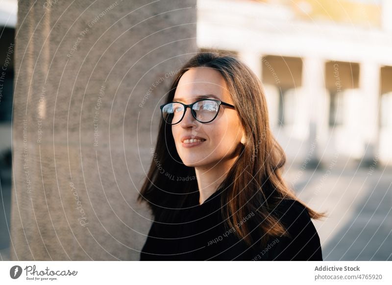 Smiling woman in eyeglasses admiring sunny street positive admire happy individuality portrait carefree charming smile dreamy female millennial sunlight enjoy