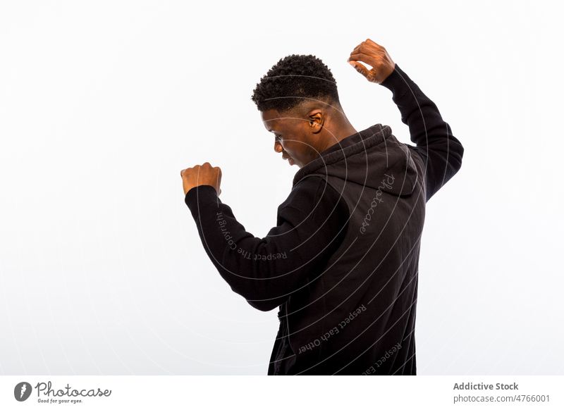 Ethnic man with raised arms in studio model personality individuality style appearance hoodie arms raised portrait male ethnic young curly hair black short hair