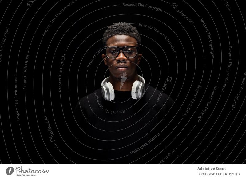 Black guy with headphones in dark studio man human face using glasses model portrait personality eyeglasses individuality style appearance meloman unshaven