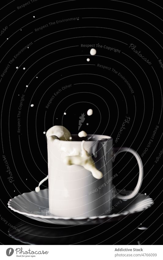 Cup with milk splashes in motion drop splatter mug fly wet drink breakfast plate beverage dairy droplet table ceramic portion cup still life liquid saucer