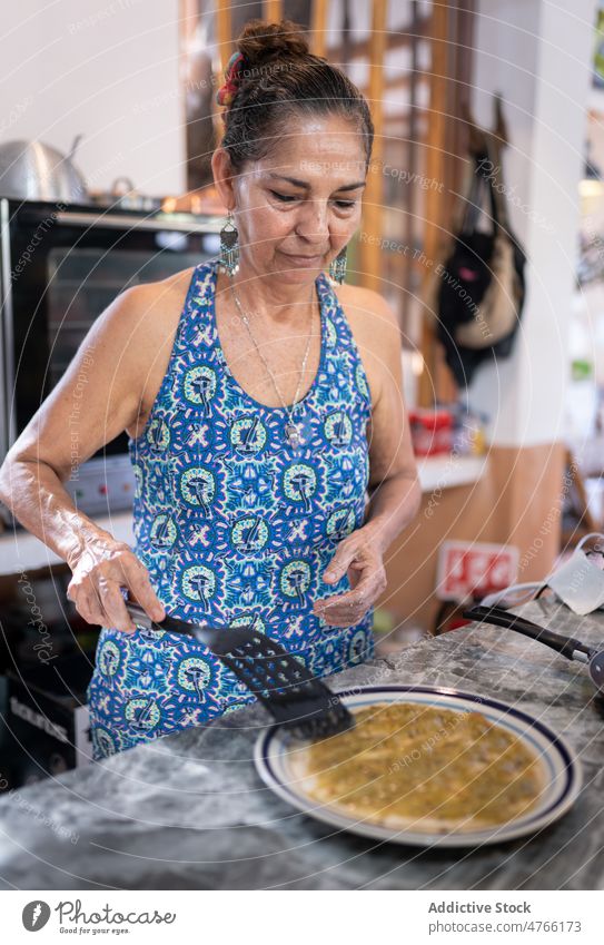Mexican woman spreading sauce on tortilla Mexican food cook dish culinary meal cuisine hispanic mexican ethnic mixed race kitchen delicious add tasty yummy