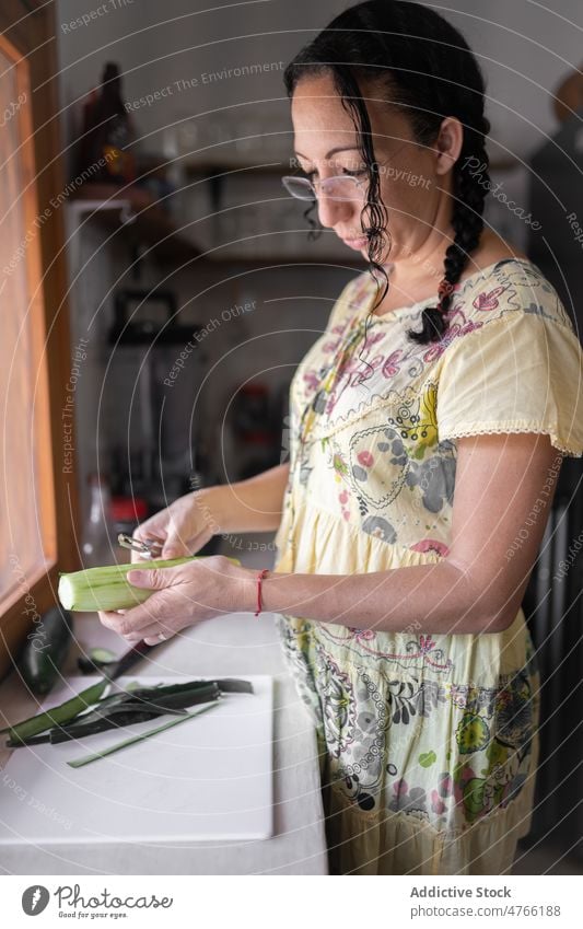 Mexican woman peeling cucumber in kitchen vegetable cook culinary cuisine food healthy food mexican ethnic mixed race hispanic fresh prepare female focus