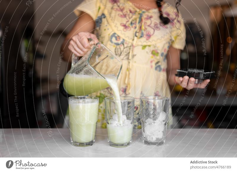 Unrecognizable woman pouring smoothies into glass cucumber kitchen appliance detox healthy drink refreshment antioxidant equipment counter supply natural