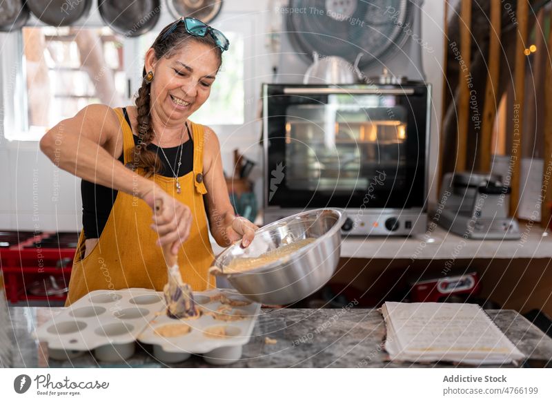 Mexican woman putting cupcake batter into baking pan Mexican food kitchen dessert bakery cook culinary cuisine mexican hispanic ethnic mixed race female fresh