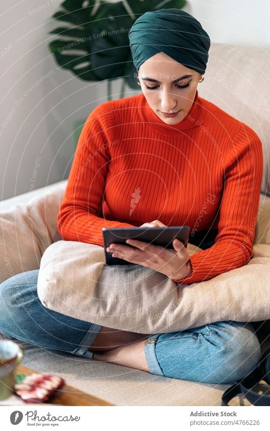 Muslim woman using tablet on couch portrait sofa home living room social media rest weekend online female muslim ethnic islam gadget device browsing internet