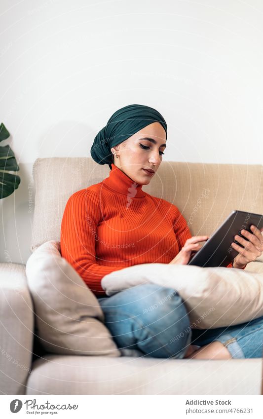 Muslim woman using tablet on couch portrait sofa home living room social media rest weekend online female muslim ethnic islam gadget device browsing internet