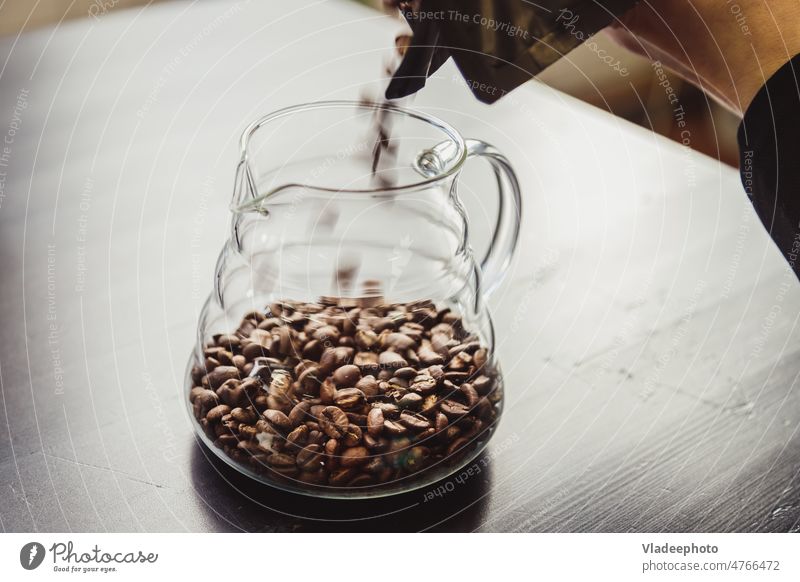 Woman pouring coffee beans into vintage grinder at countertop indoors, closeup wooden roasted natural table old glass flavor energy drink cofee caffeine brown