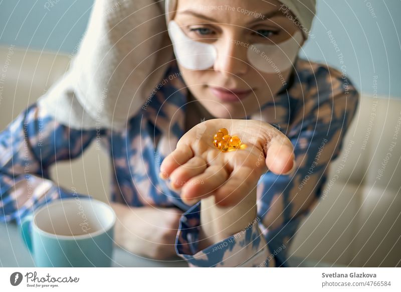 Close up of woman with pill cod liver oil Omega-3. Holding soft shell D-vitamin capsule. Diet nutrition and healthy concept. Selective focus. Vitamin E, A Fish Oil