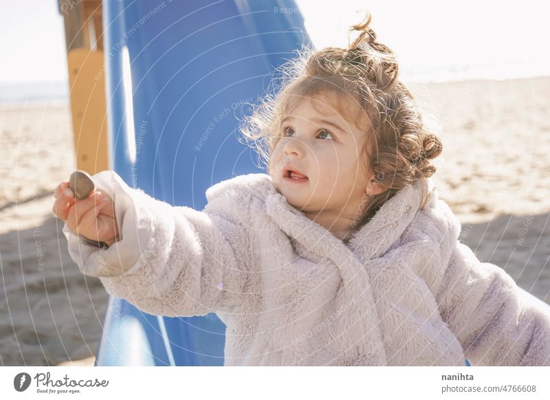Little girl giving a stone to her father in the playground toddler give gift share face lovely cute slide curly hair fur coat winter happy solidarity generosity