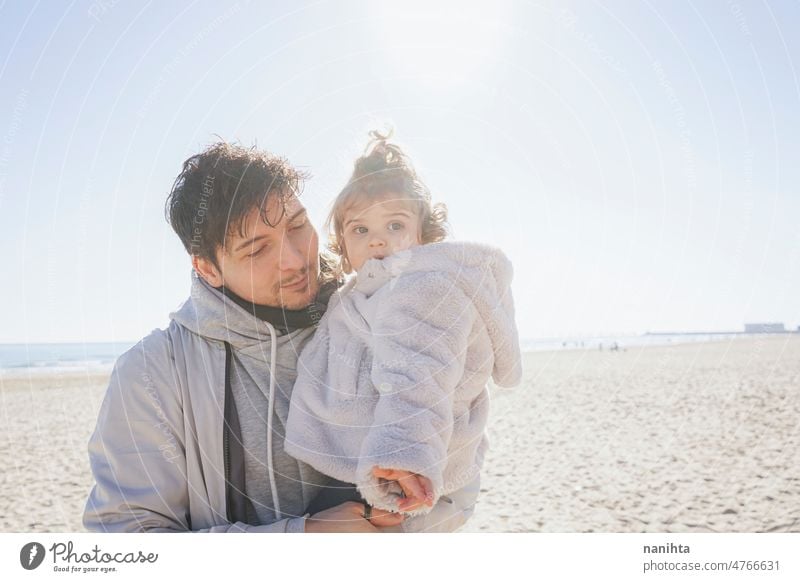 Single dad carring her baby in a sunny day single parent family affection toddler hug carry girl daughter beach winter sunshine love backlight new modern