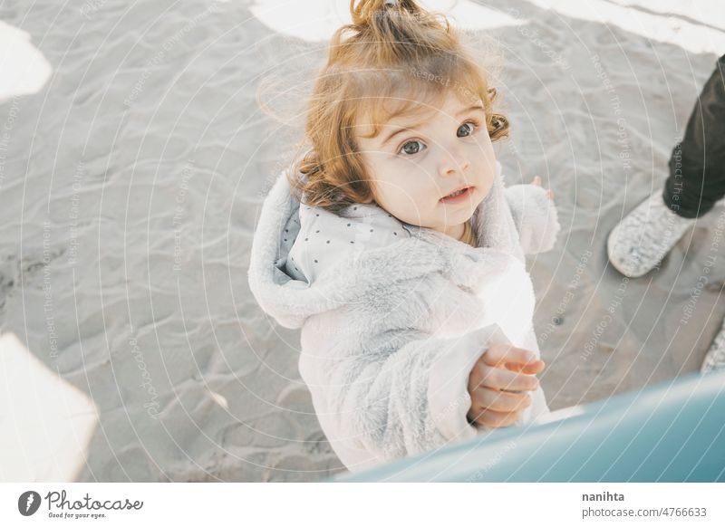 Portrait of a little girl in a winter sunny day playful baby portrait outdoors curly beach adorable cute hair lovely toddler european spanish sand childhood
