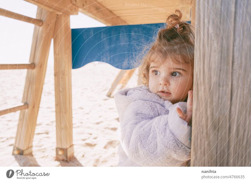 Little girl enjoying a winter sunny day at the beach playground toddler happy curious playful explore family adorable lovely childcare childhood emotion mood