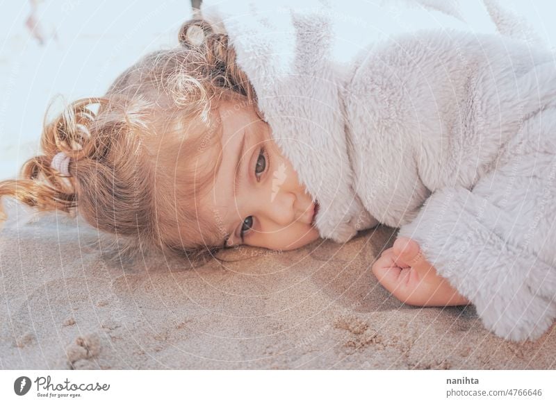 Portrait of a little girl in a winter sunny day playful baby portrait outdoors curly beach adorable cute hair lovely toddler european spanish sand childhood