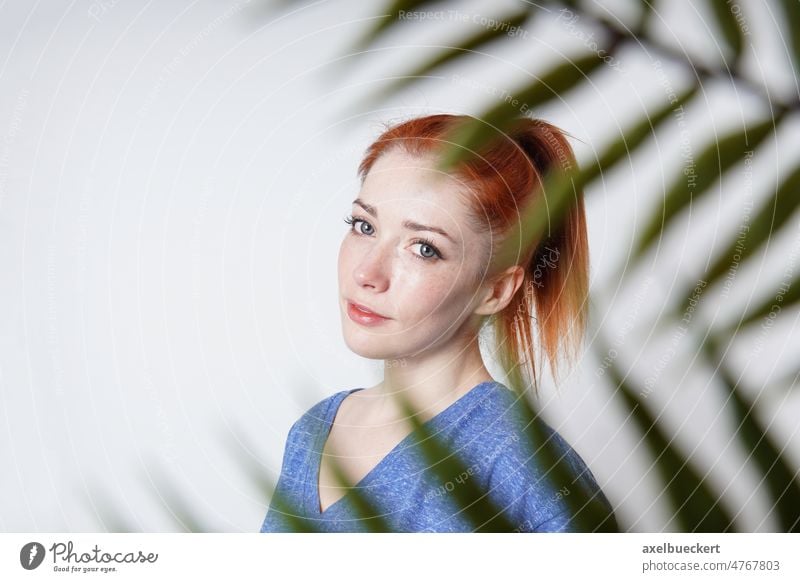 indoor portrait of young woman shot through plant leaves leaf girl wellbeing clean living behind real authentic female person people copy space copyspace happy