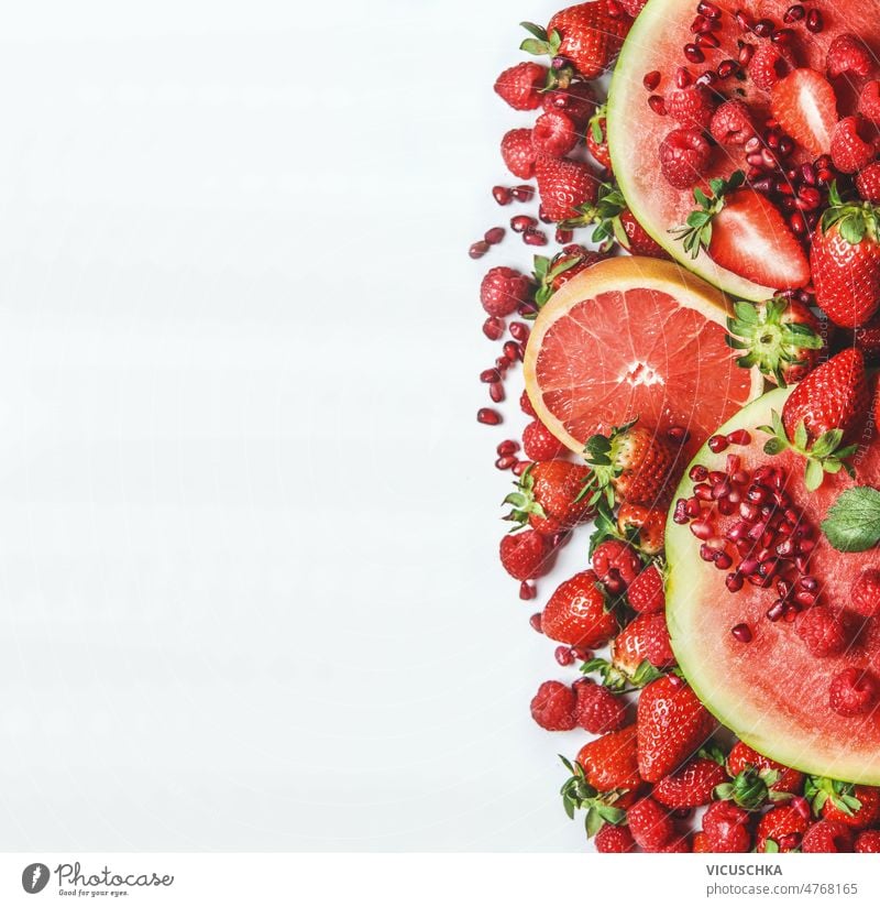 Red fruits and berries on white background. Watermelon, grapefruit, strawberries, raspberries and pomegranate seeds red watermelon healthy summer snack border