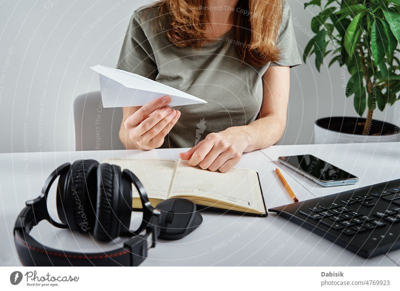 Woman plays with paper plane at workplace lazy distracted procrastination woman home office unproductive remote avoid bored business communication computer