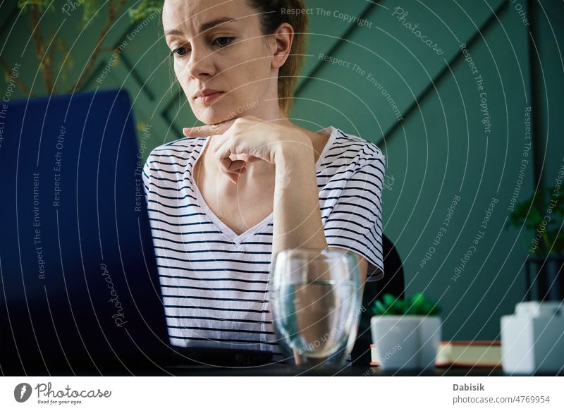 Woman working remotely at home office with laptop workplace freelancer business busy overwork table water glass plant woman computer girl interior lifestyle