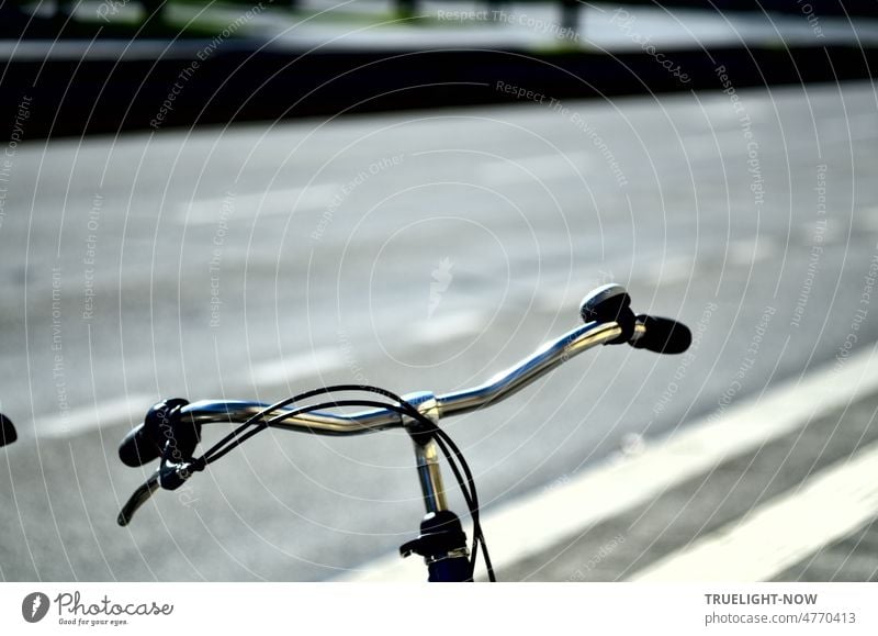 Ladies bike handlebar minimalism: chrome shiny handlebar with handbrake, brake cable and bell parked on a wide road with white lane markings running dynamically diagonally through the image
