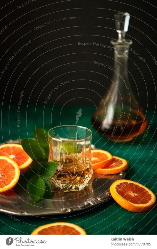 Scene with glass of whiskey, oranges, decanter, and jade green background Food drink beverage alcohol Cocktail vintage elegant still life food still live